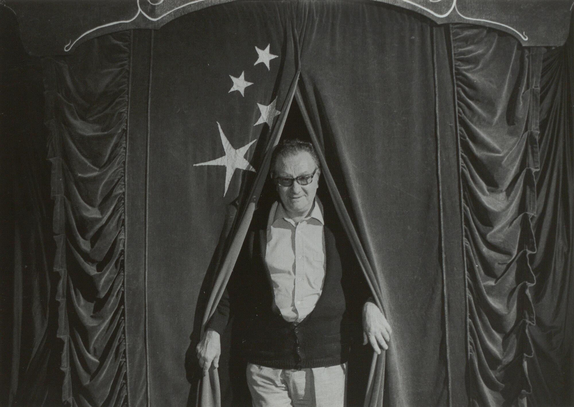 Retrato de Joan Brossa saliendo de un telón de la compañía Circ Perillós